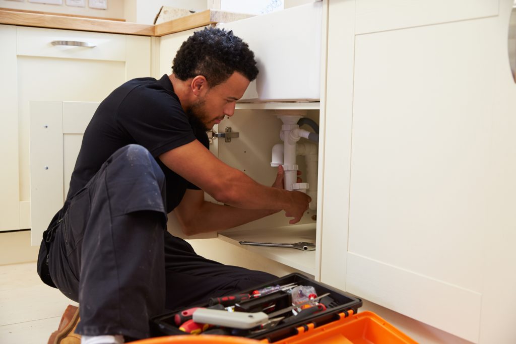 A plumber fixing a sink's pipe