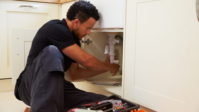 A plumber fixing a sink's pipe