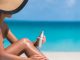 Bikini hat woman applying sunscreen lotion on tanned legs