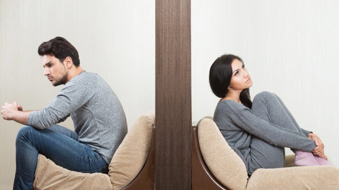 Conflict between man and woman sitting on either side of a wall