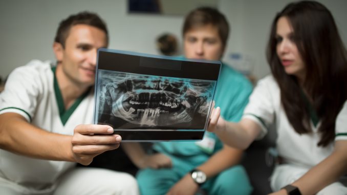 Dentist explaining to assistant the progression of tooth loss