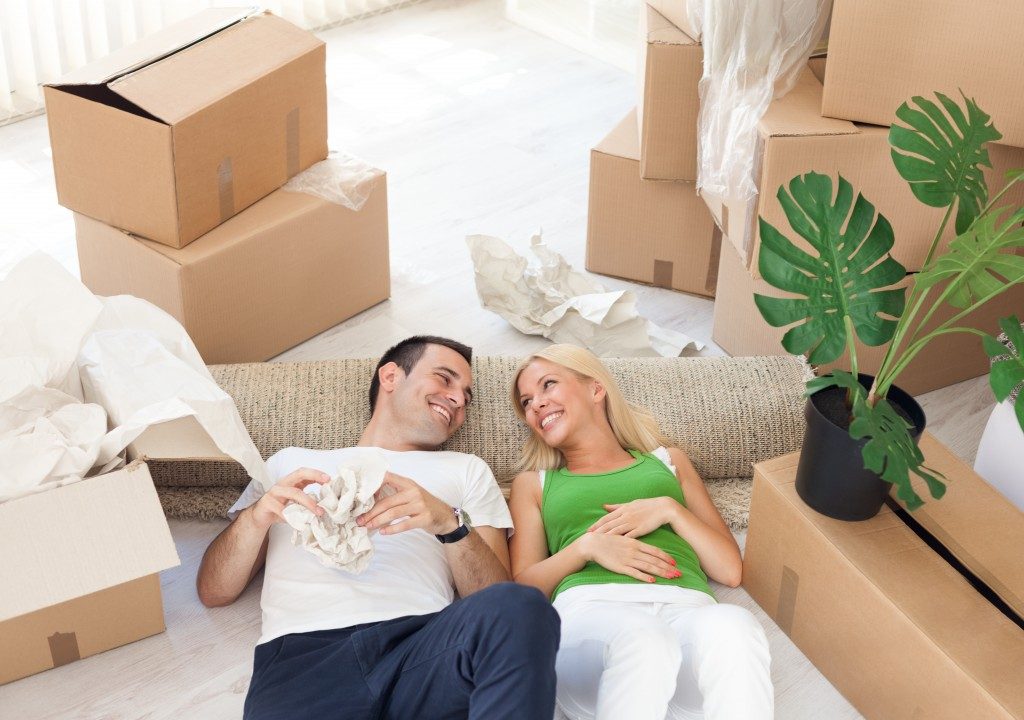 Young smiling couple relaxing in the middle of cardboard boxes in new home