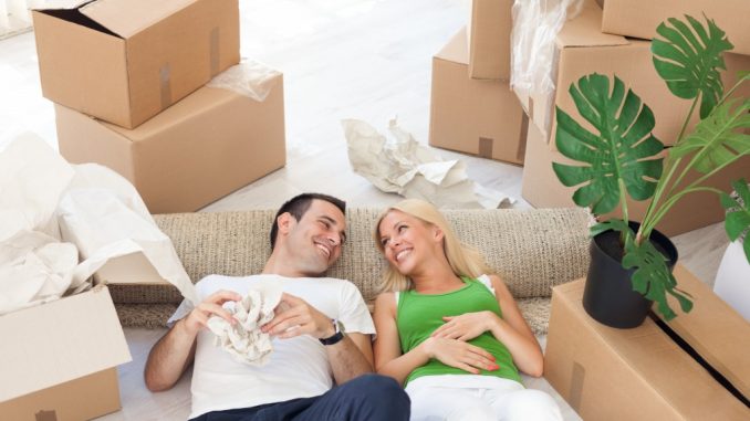 Young smiling couple relaxing in the middle of cardboard boxes in new home