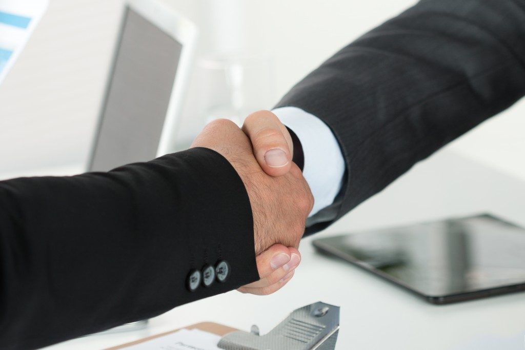 two businessman shaking hands with each other in the office after business sale