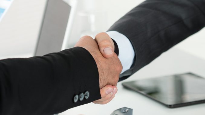 two businessman shaking hands with each other in the office after business sale