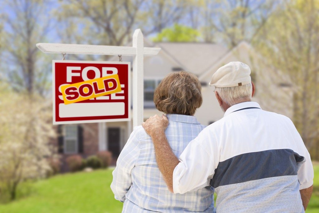 an old couple standing in front of a house they just bought