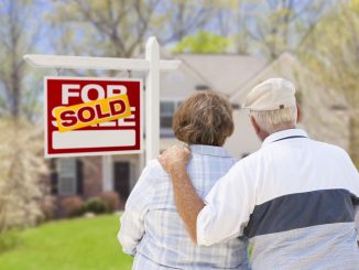 an old couple standing in front of a house they just bought
