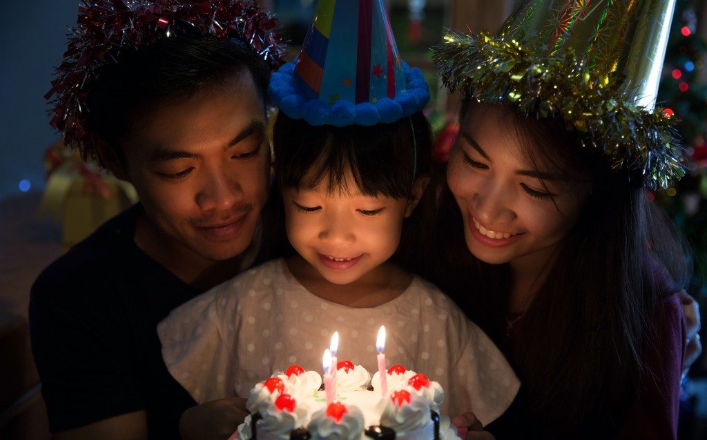 Birthday girl about to blow candles with parents