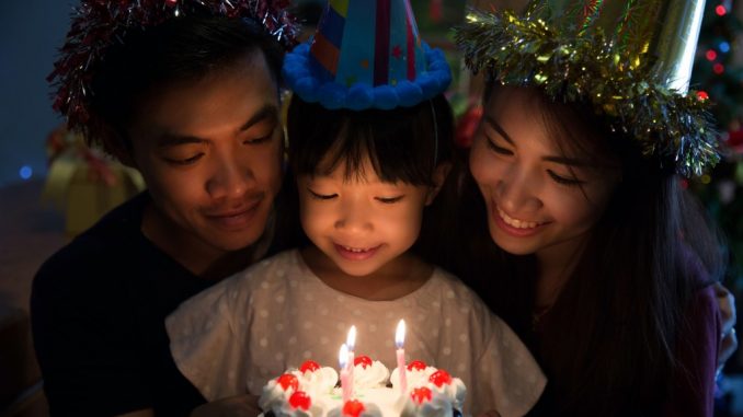 Birthday girl about to blow candles with parents