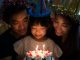 Birthday girl about to blow candles with parents