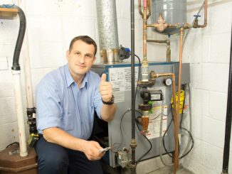 Plumber posing beside a gas furnace