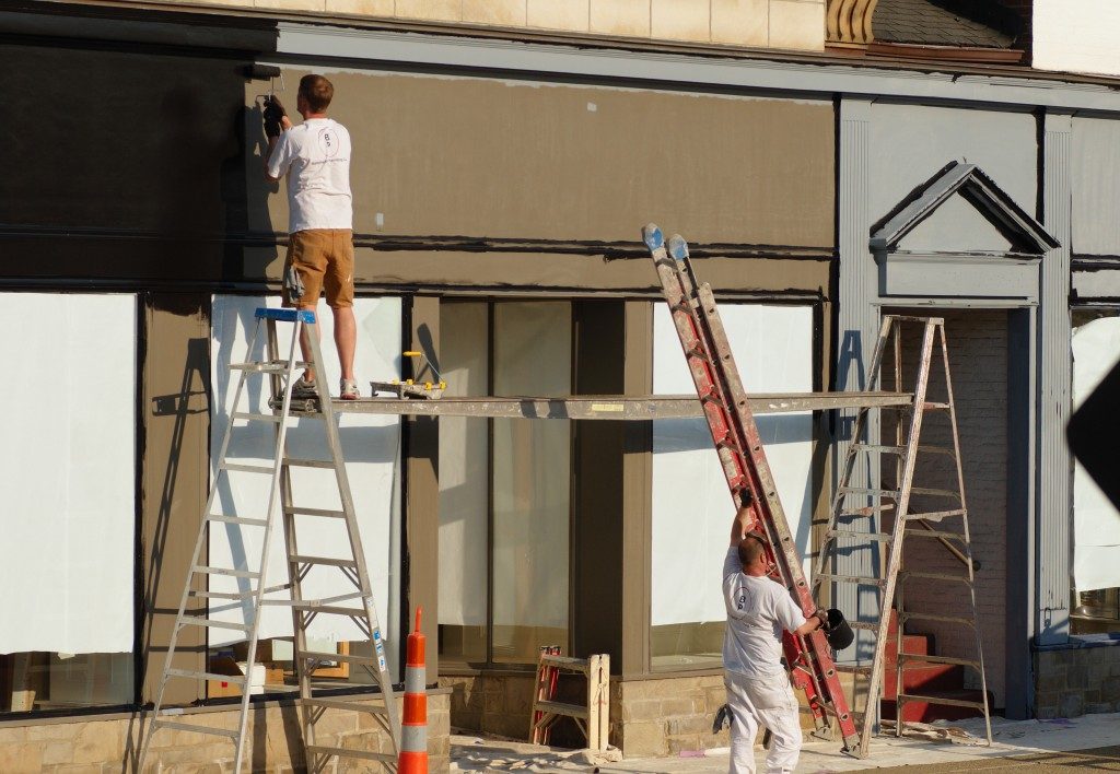 men outside painting the front side of the house