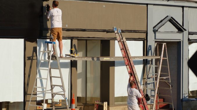 men outside painting the front side of the house