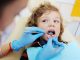 kid having his teeth checked by dentist