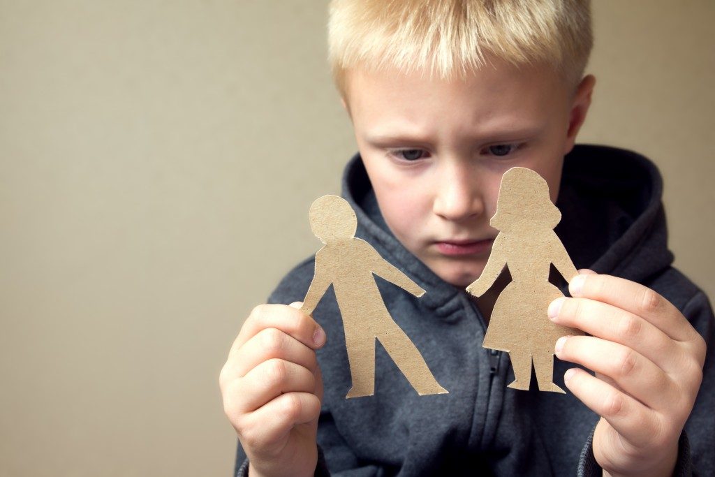 Child holding a cut out of a man and woman representing his parents