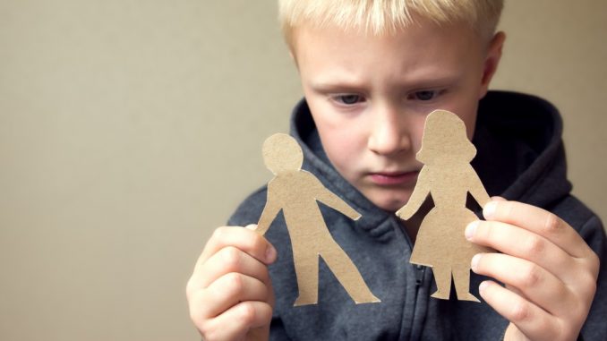 Child holding a cut out of a man and woman representing his parents