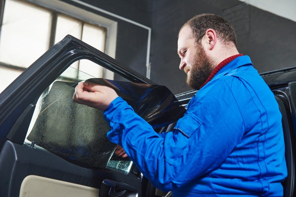 man installing tint on car