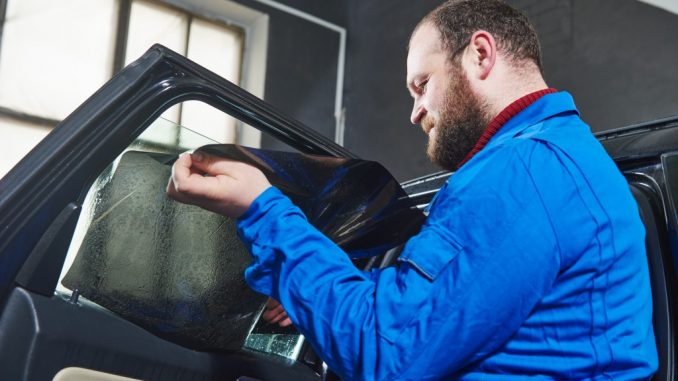 man installing tint on car