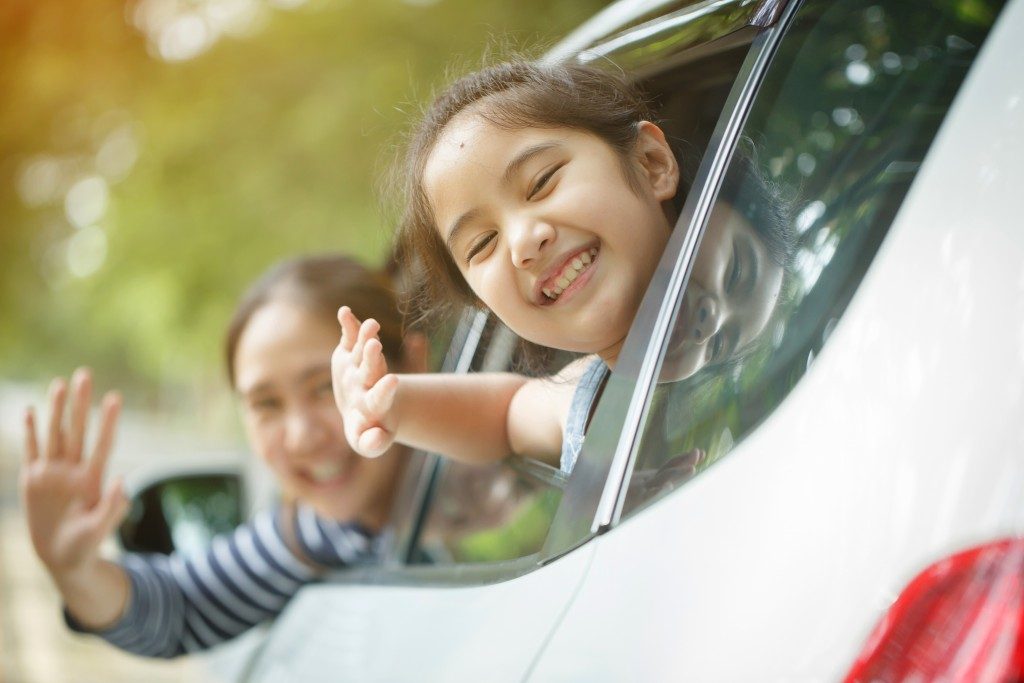 child and mother waving in the car