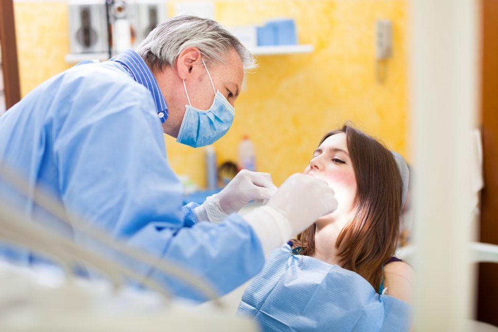 senior dentist foused while treating his patient