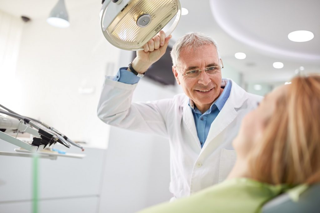 senior dentist adjusting the light before the treatment his patient