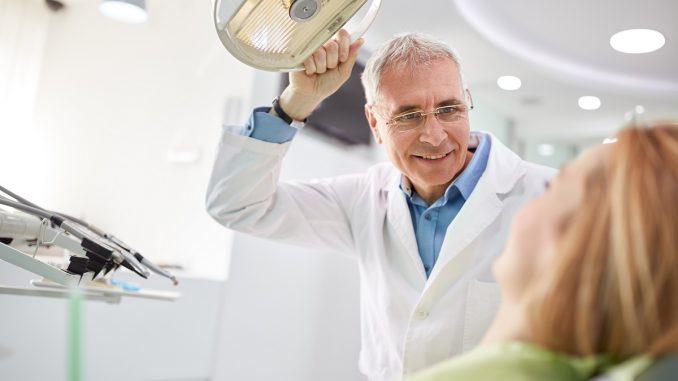 senior dentist adjusting the light before the treatment his patient