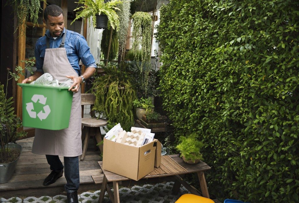 Man carrying recycle bin and box outside