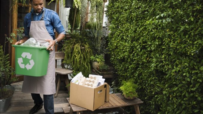 Man carrying recycle bin and box outside