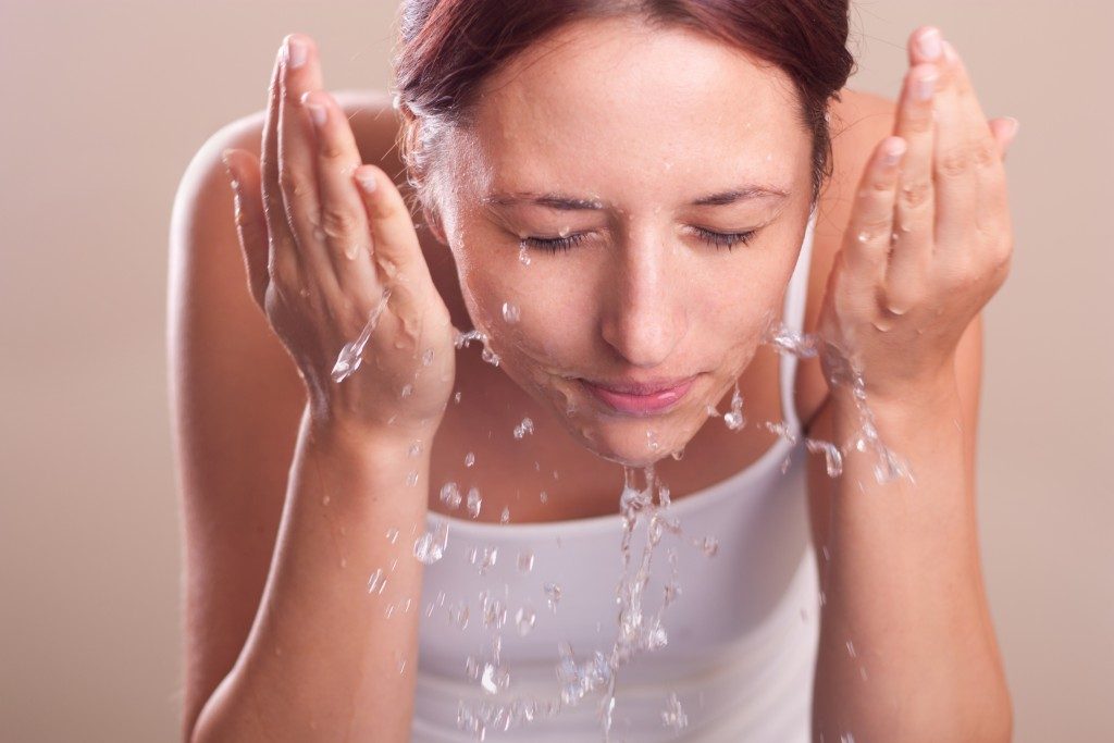 woman washing her face with water