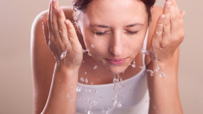 woman washing her face with water