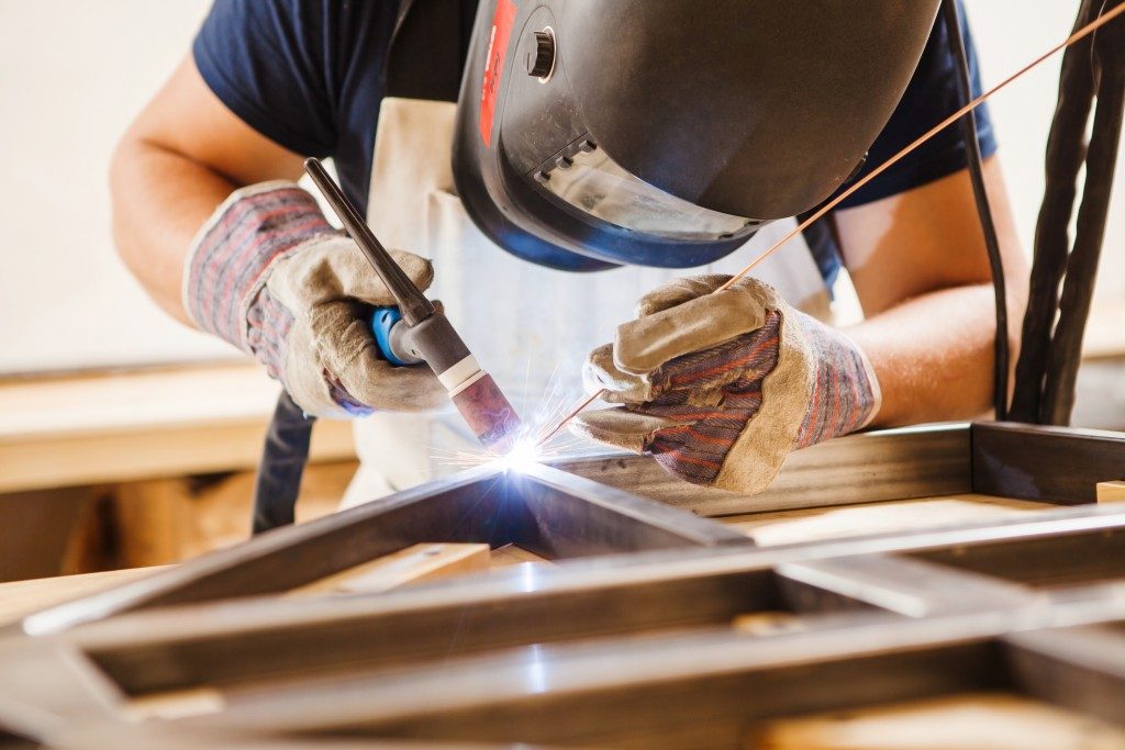 Male in face mask welds argon