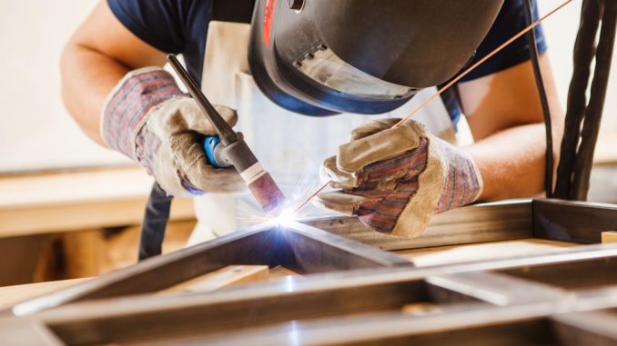 Male in face mask welds argon