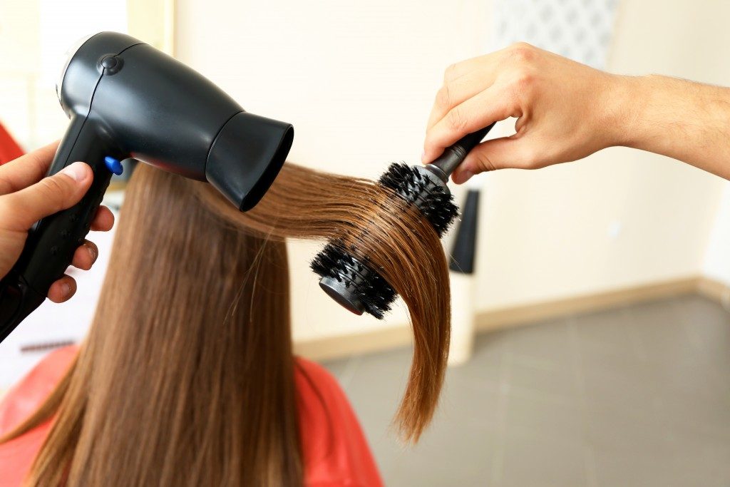 straightening woman's hair in a salon