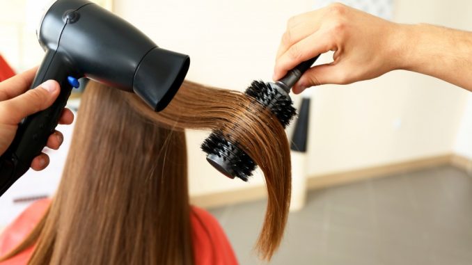 straightening woman's hair in a salon