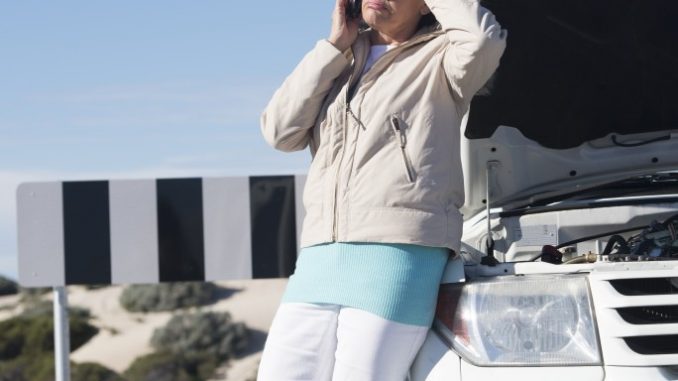 woman on the phone on the side of ride broken down car