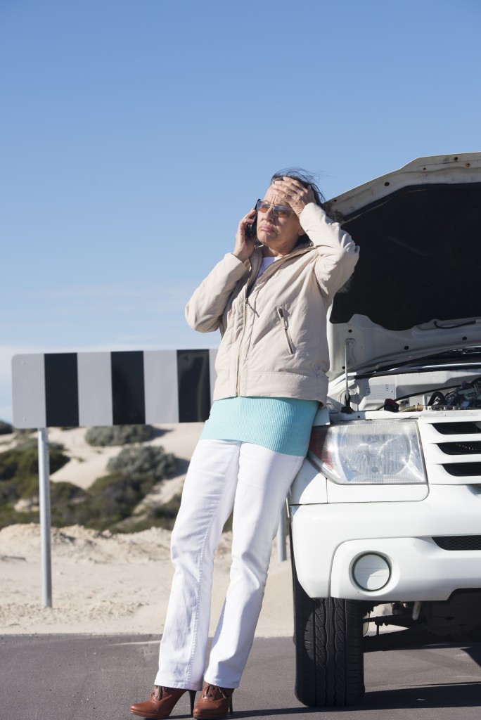 woman on the phone on the side of ride broken down car