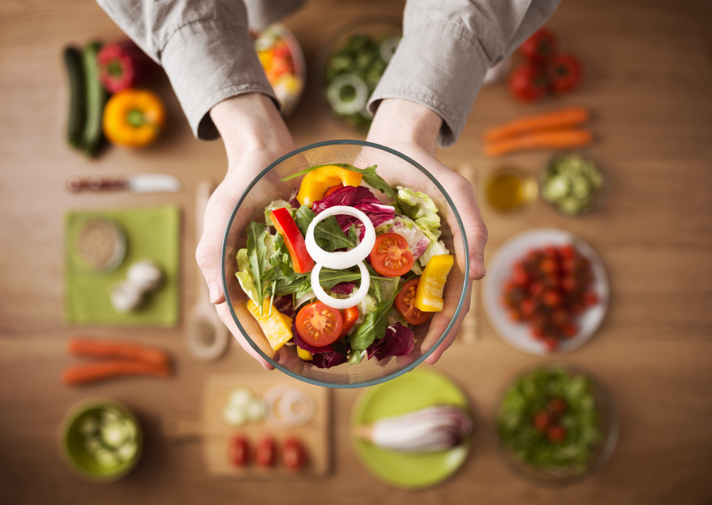 hand holding a bowl of vegetables